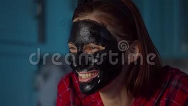 滑稽的30多岁的女人，脸上戴着黑色化妆面具，在家里做<strong>鬼脸</strong>。 戴着蓝色面具做<strong>鬼脸</strong>的女人